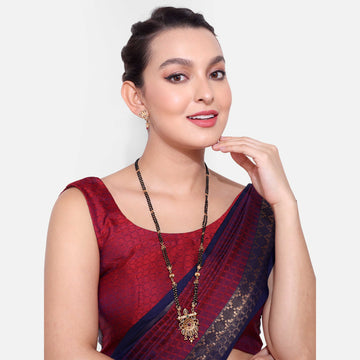 Woman wearing a traditional long mangalsutra necklace with black beads and gold pendant styled with a red and navy saree