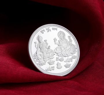 925 sterling silver coin with detailed Lakshmi and Ganesha engravings on red fabric background