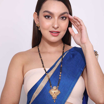 Woman wearing a traditional long mangalsutra necklace with black beads and gold pendant in blue saree