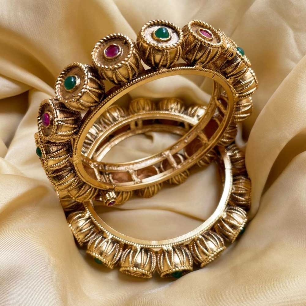 Close-up of ornate gold Festive Bangles with red and green stones on silky fabric background