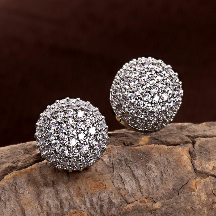 Round silver studs earring with sparkling crystals on textured stone background