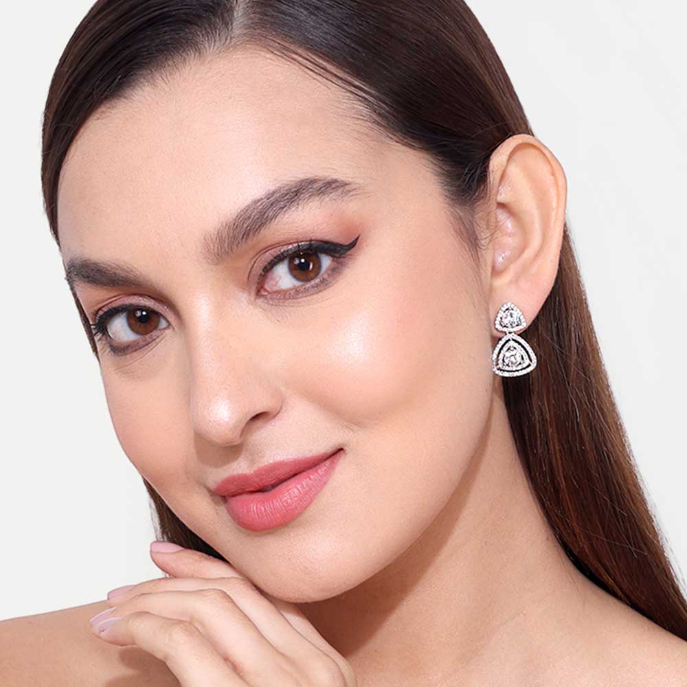 Close-up of woman wearing elegant silver earring with detailed design on white background