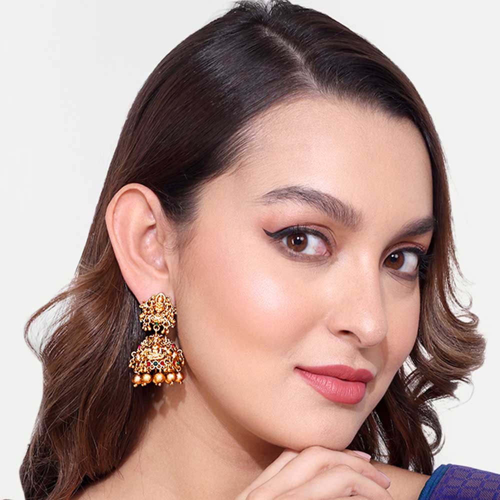 Close-up of woman wearing traditional gold Jhumkas earring with intricate design and pearl details