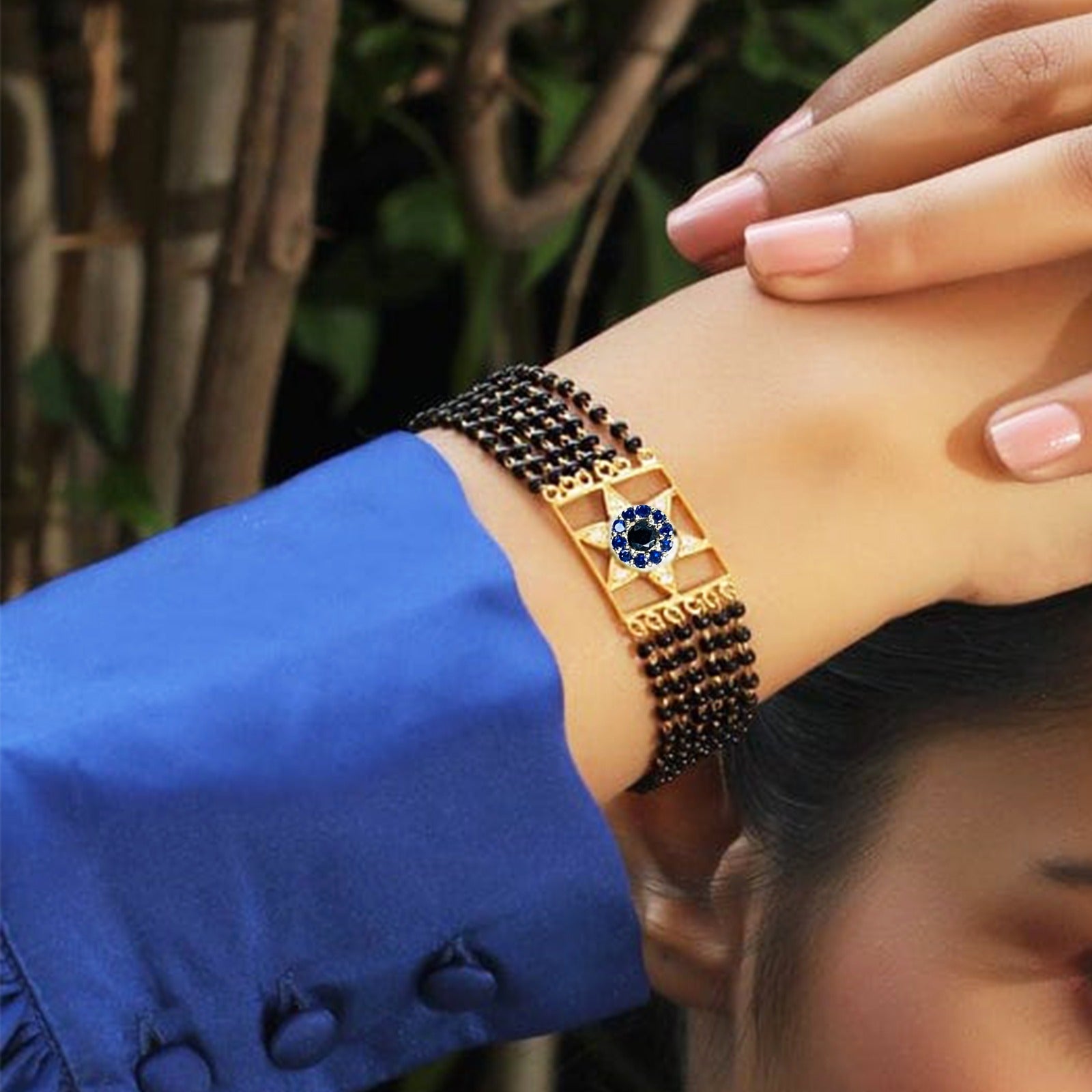 Elegant Hand Mangalsutra bracelet featuring intricate gold detailing and a gemstone design on a wrist.