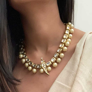 Elegant Kundan Necklaces featuring gold settings and pearl accents worn on neck with beige attire