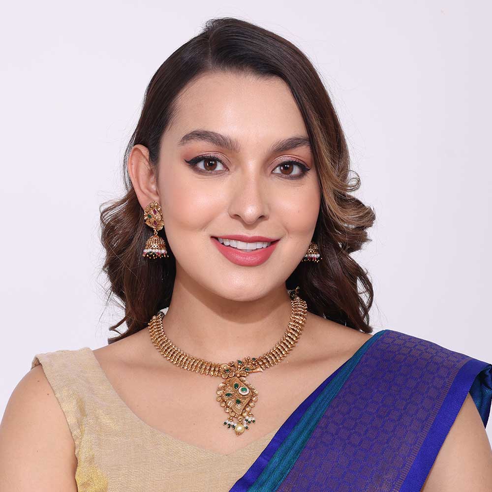 Woman wearing elegant gold necklaces with traditional pendant and matching earrings in ethnic attire