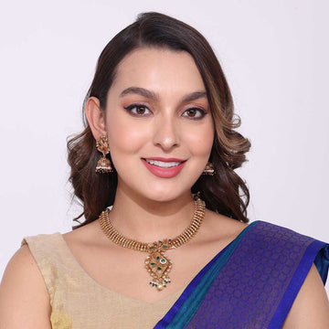Woman wearing elegant gold necklaces with traditional pendant and matching earrings in ethnic attire