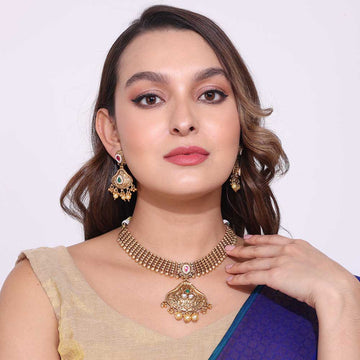 Woman wearing a gold festive necklace with matching earrings and traditional attire showcasing festive necklaces