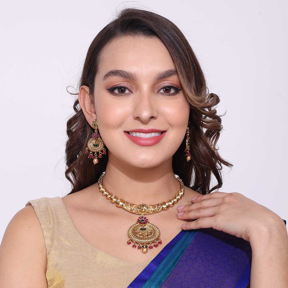Woman wearing an elegant gold antique necklaces and matching earrings with traditional Indian attire