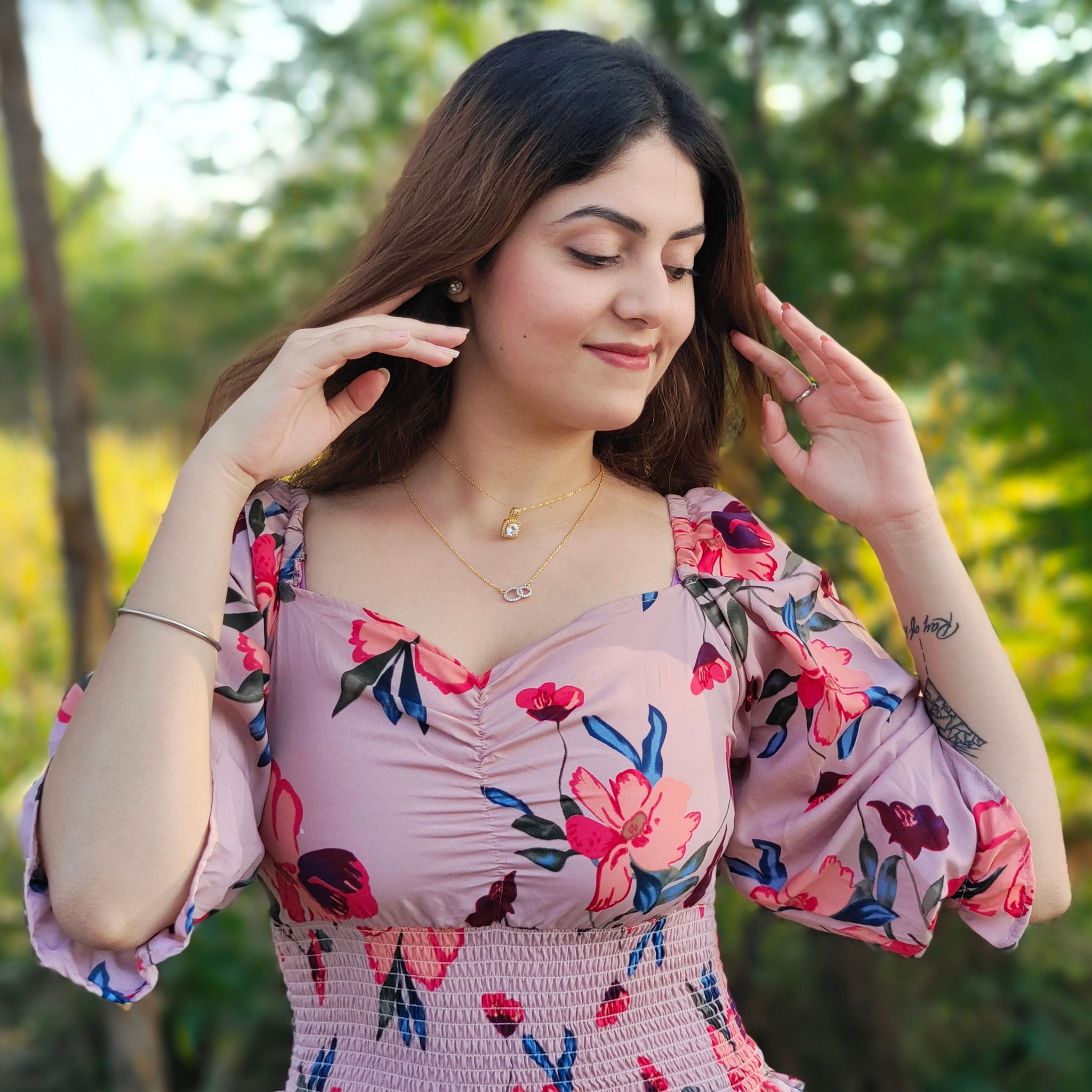 Woman wearing influencer style gold layered necklaces and floral dress outdoors