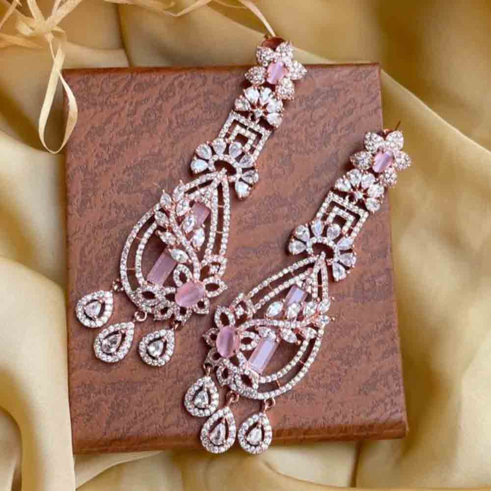 Elegant pair of rose gold earring with intricate design and pink gemstone accents displayed on a textured box