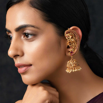 Elegant gold temple earrings with intricate traditional design worn by woman in close-up