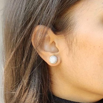 Close-up of a woman's ear wearing a round silver casual earring with textured detailing