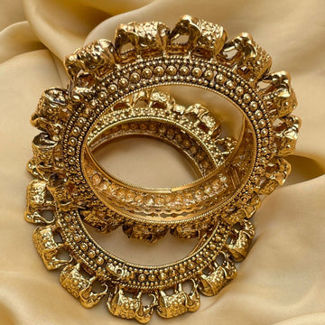 Intricately designed gold Temple Bangles with elephant motifs displayed on beige fabric