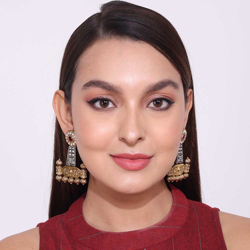 Close-up of woman wearing dual tone earrings with intricate design and pearl accents