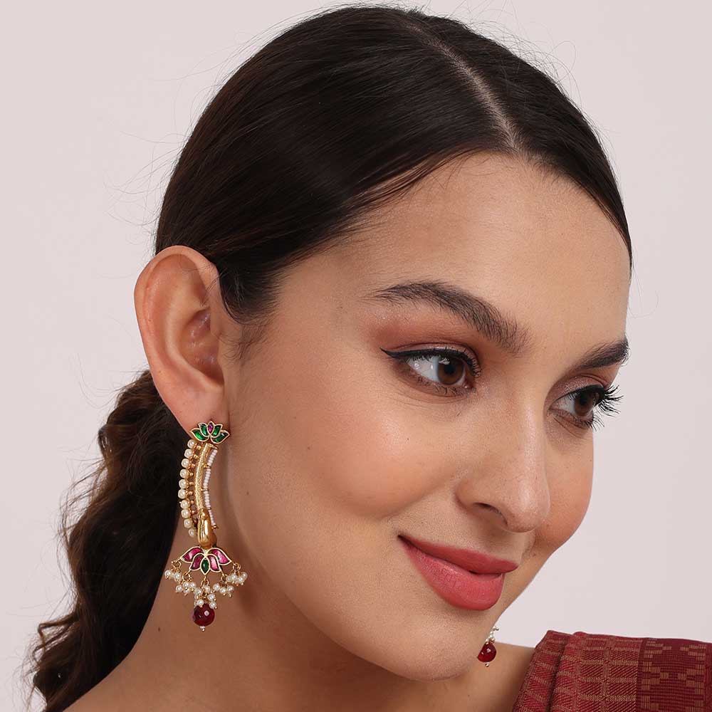 Close-up of a woman wearing a traditional gold and pearl bridal earring with red and green accents