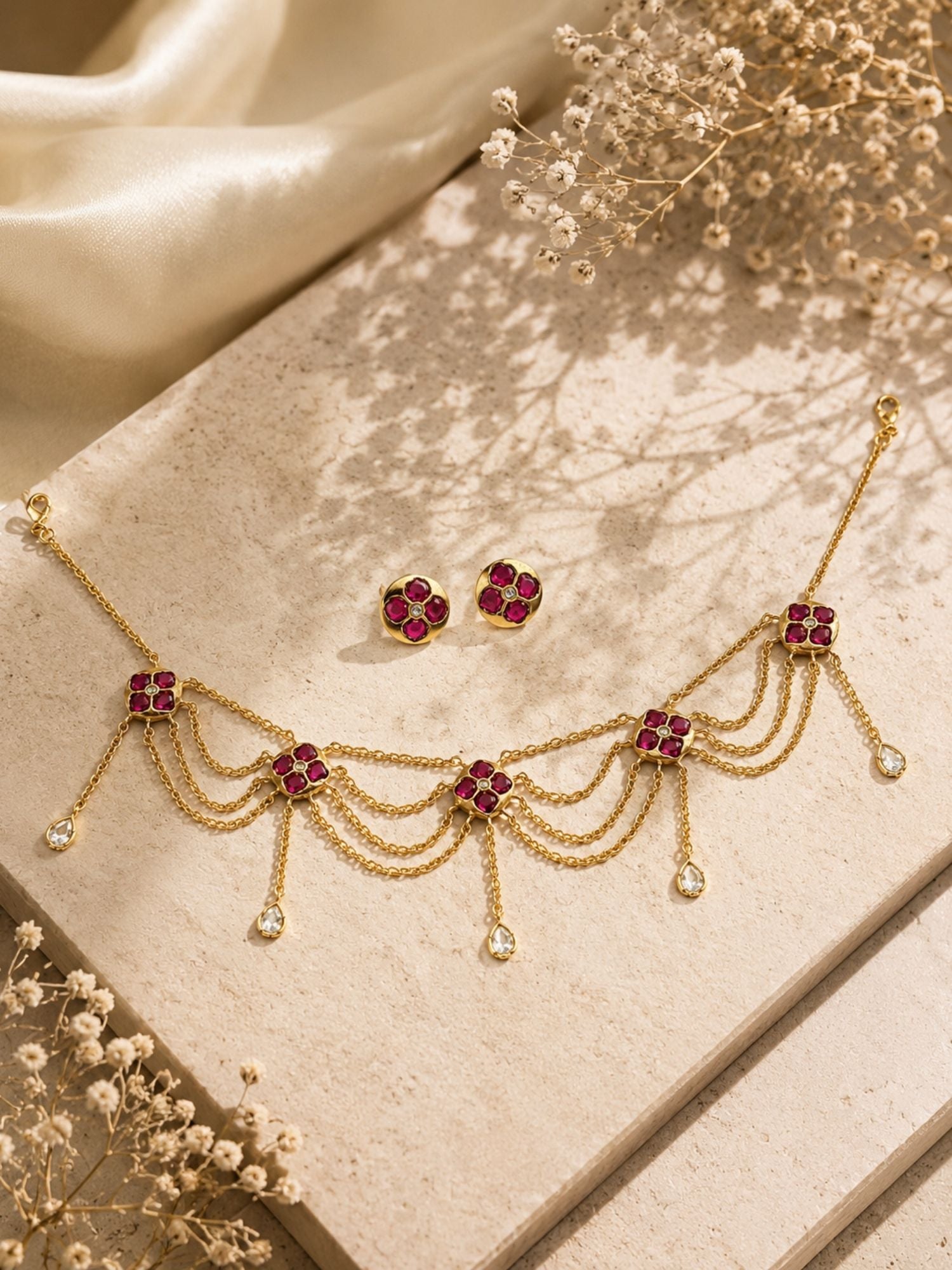 Pink Kundan floral layered chain necklace set flat lay with matching stud earrings on beige stone