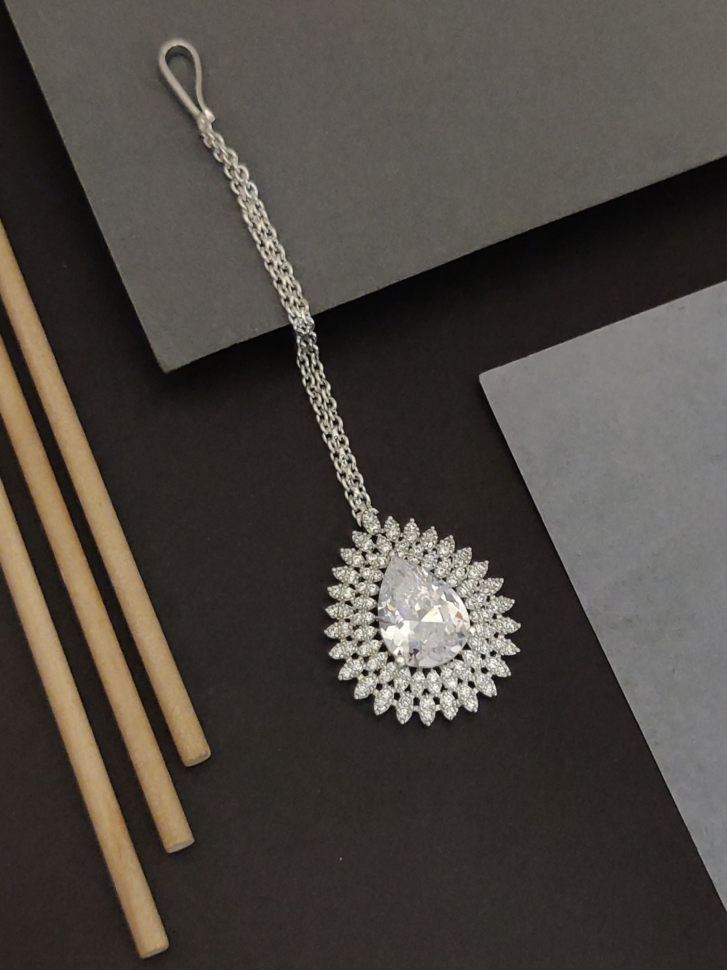 Abdesigns Gold Teardrop CZ Maangtikka. Bridal. Silver tone teardrop CZ maangtikka on chain with hook on dark background