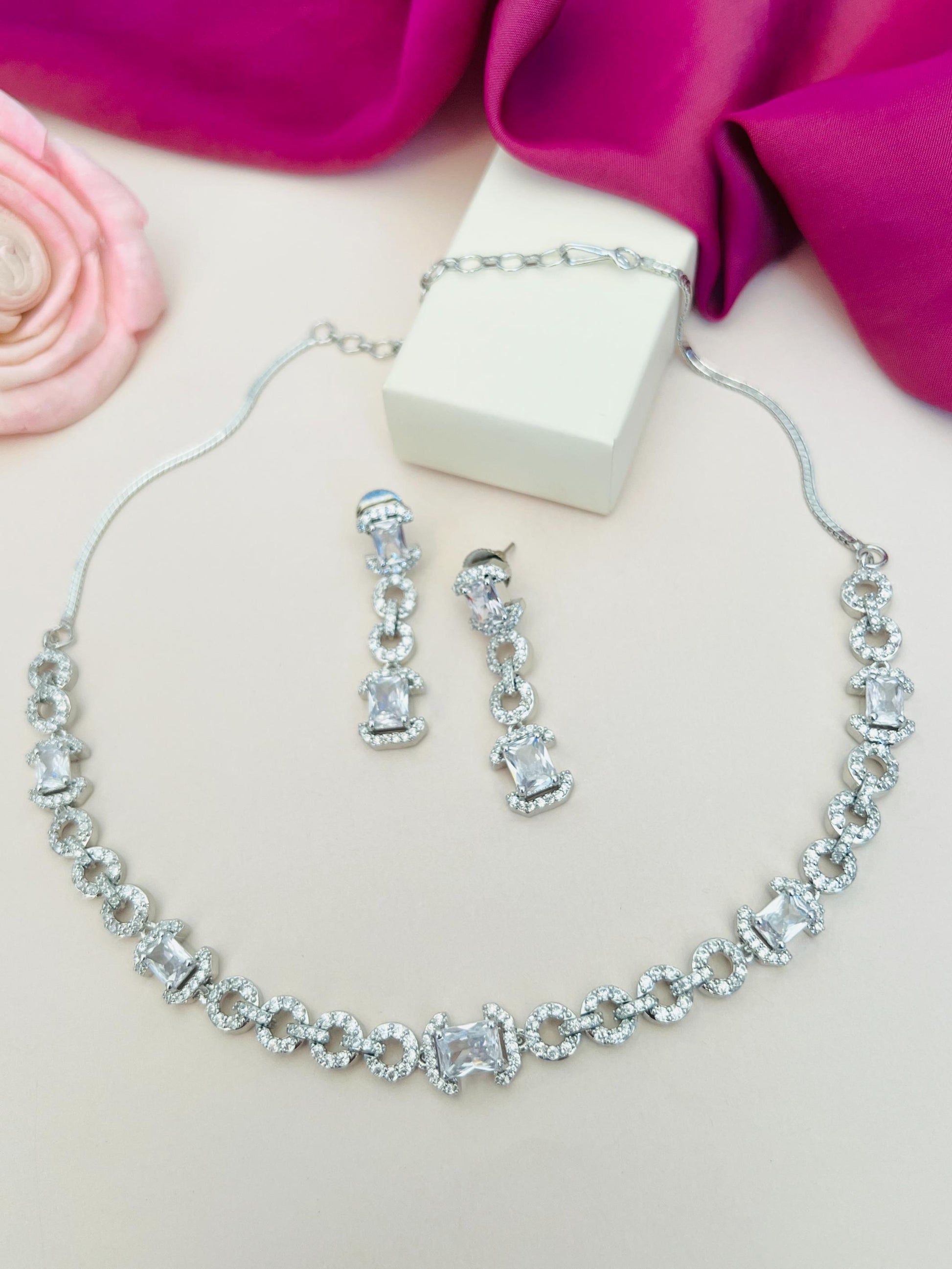 Abdesigns Jewellery Elegant Necklace with Green Gemstones photo of silver necklace and clear earrings on pink fabric