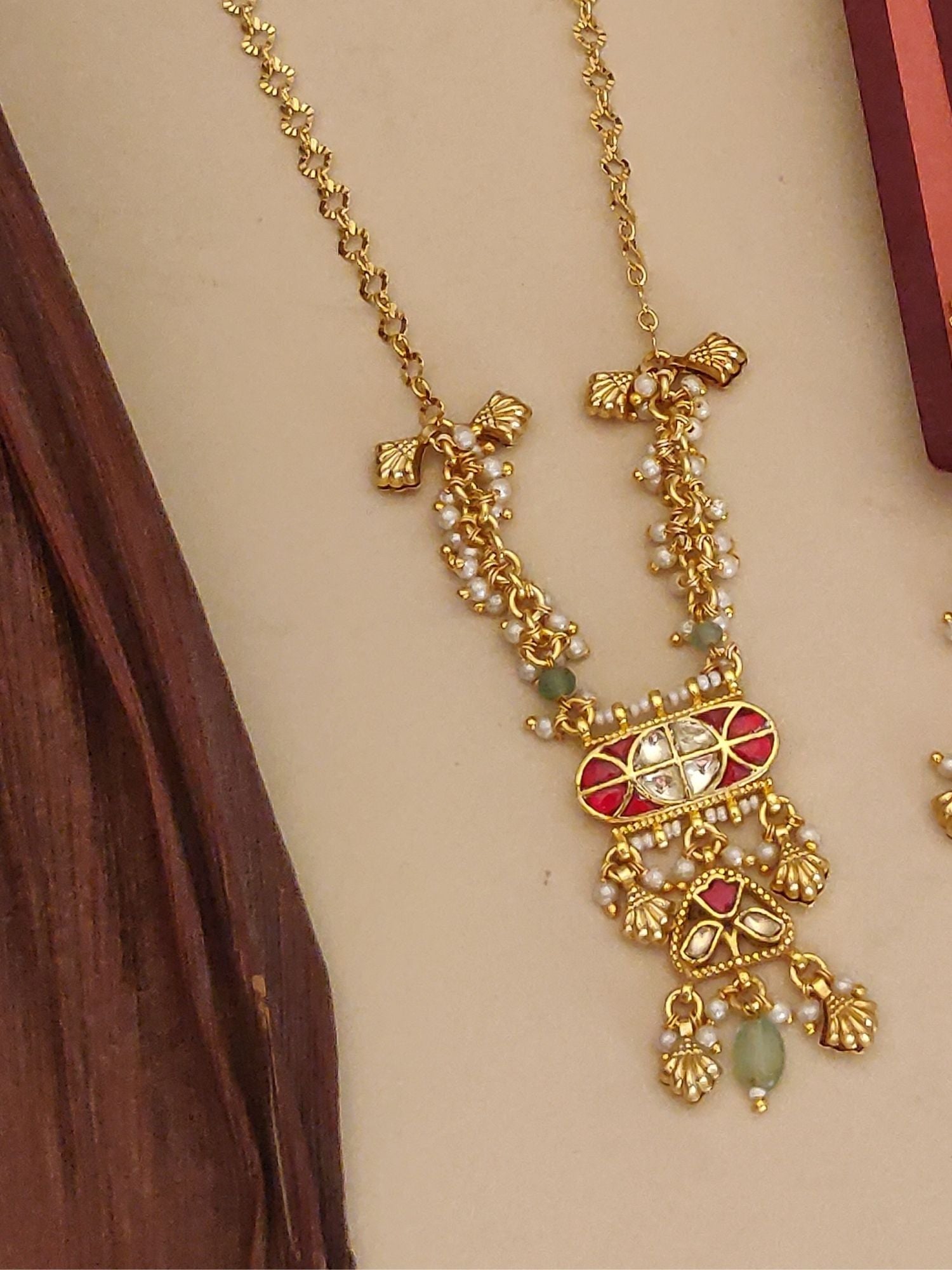 Gold necklace featuring Abdesigns Jewellery Pendents with Pearl and Red Stone Design. Dangling green beads and pearls