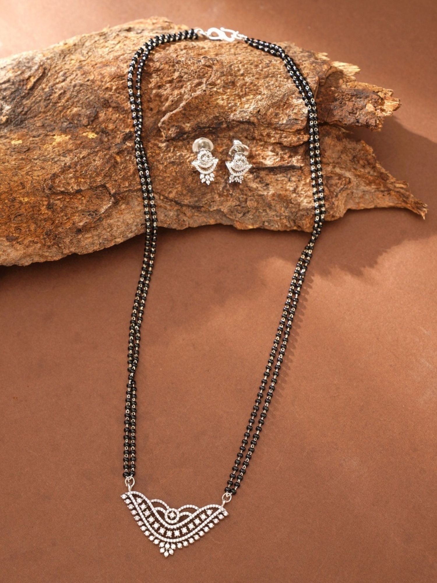 Abdesigns Jewellery Silver Plated American Diamond Mangalsutra With Earrings displayed on rustic wood background