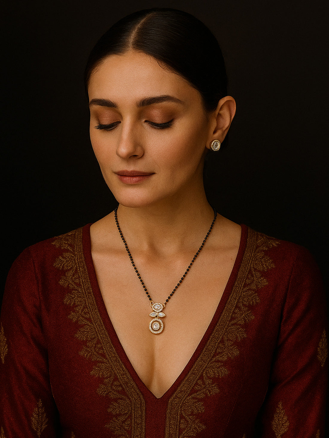 Abdesigns Luxe gold plated mangalsutra for women. Model in maroon top wearing black bead chain with twin gold pendant and earrings