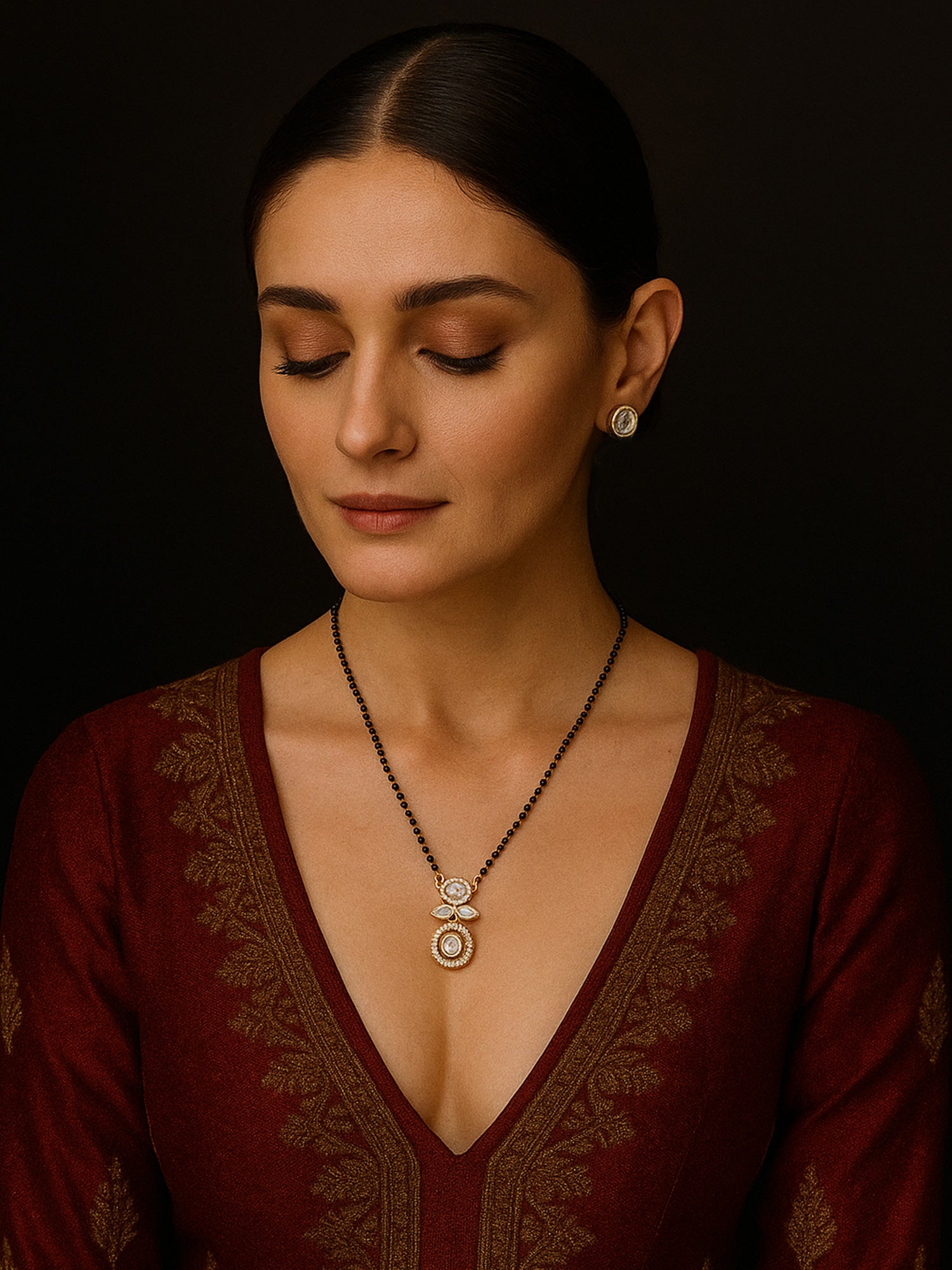 Abdesigns Luxe gold plated mangalsutra for women. Model in maroon top wearing black bead chain with twin gold pendant and earrings