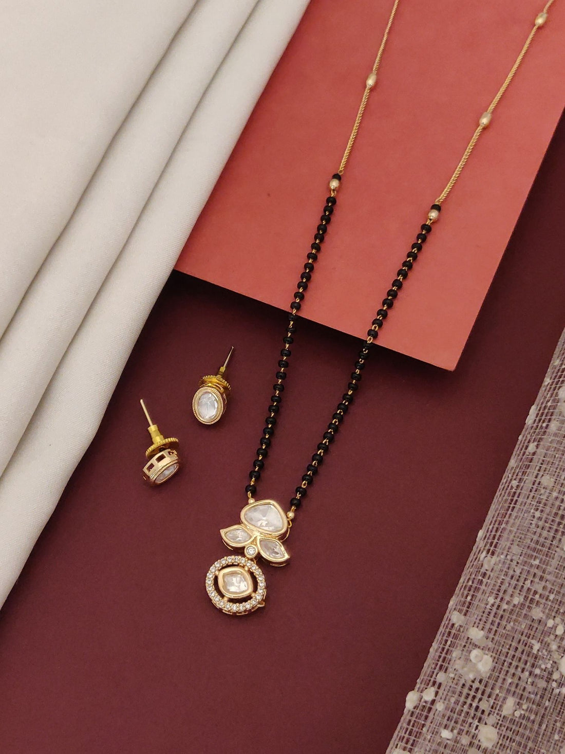 Abdesigns Luxe gold plated mangalsutra for women. Model in maroon top wearing black bead chain with twin gold pendant and earrings