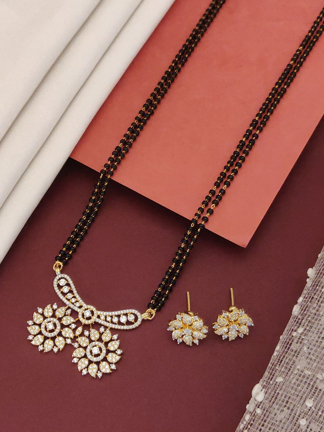 Abdesigns Mesmerizing gold plated mangalsutra for women. Floral zircon pendant and matching earrings on black beads