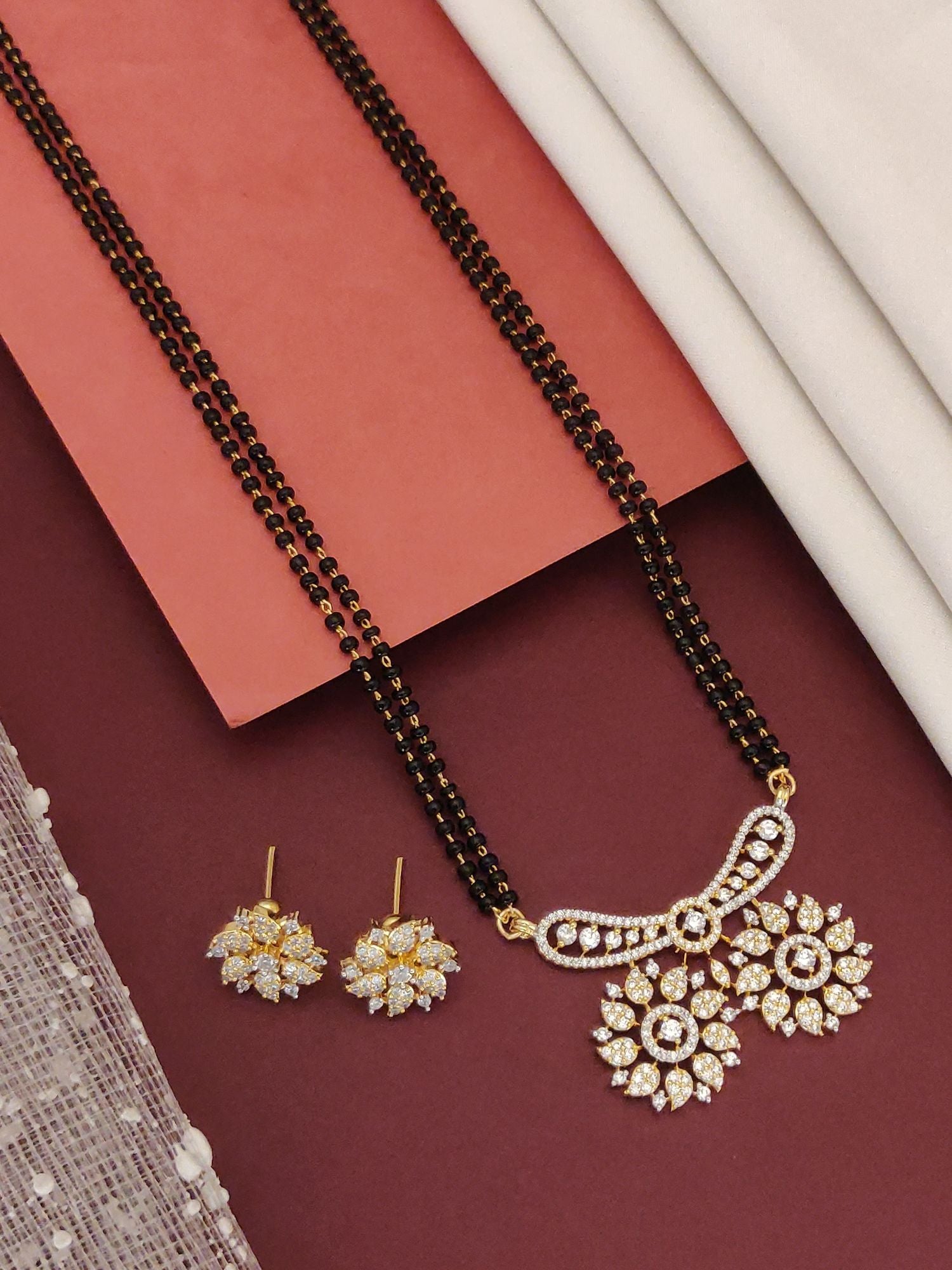 Abdesigns Mesmerizing gold plated mangalsutra for women. Floral zircon pendant and matching earrings on black beads