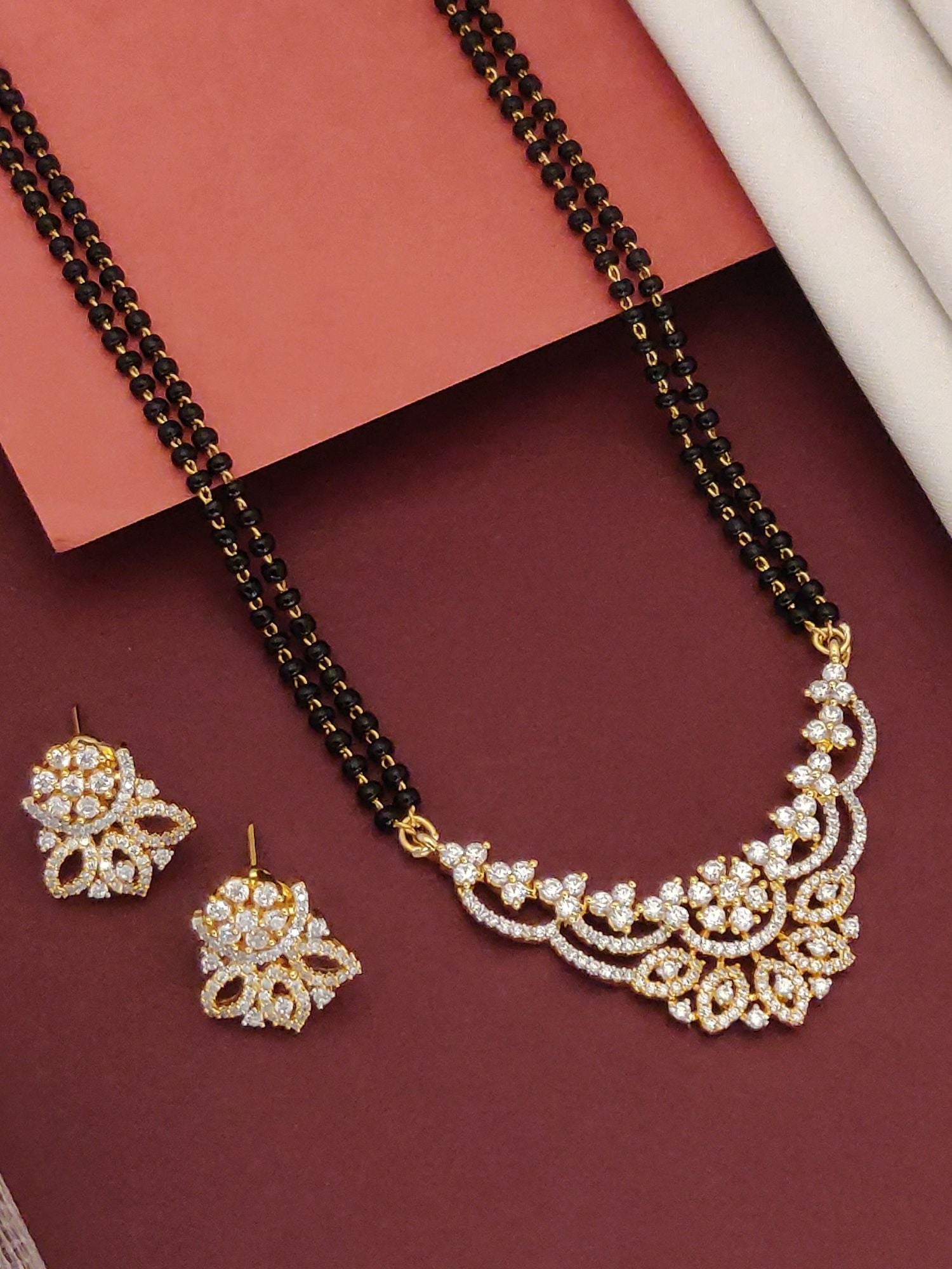 Abdesigns Opulent gold plated mangalsutra for women. Gold plated mangalsutra with black beads floral CZ pendant and earrings