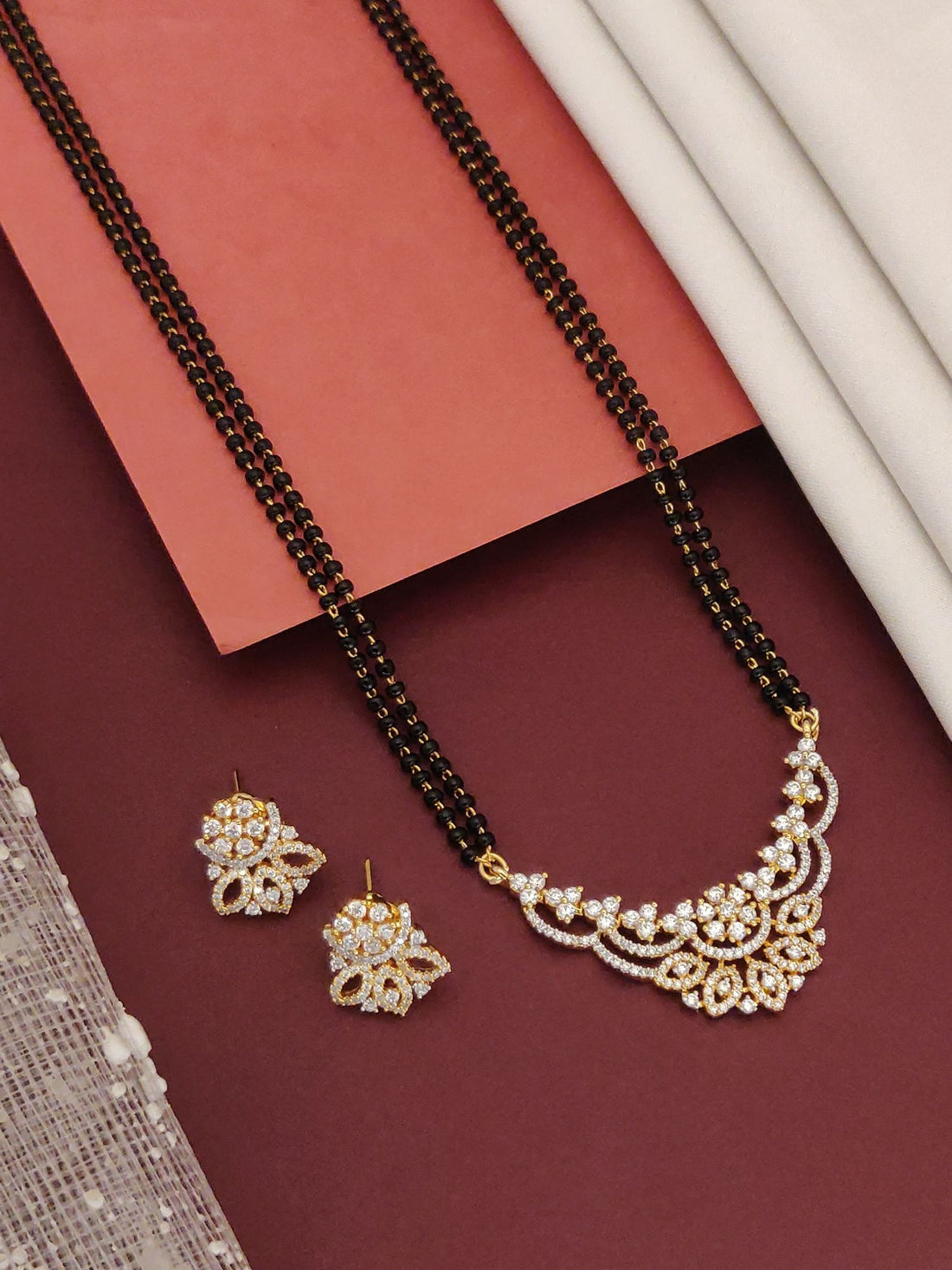 Abdesigns Opulent gold plated mangalsutra for women. Double black bead chain with floral white stone pendant plus earrings