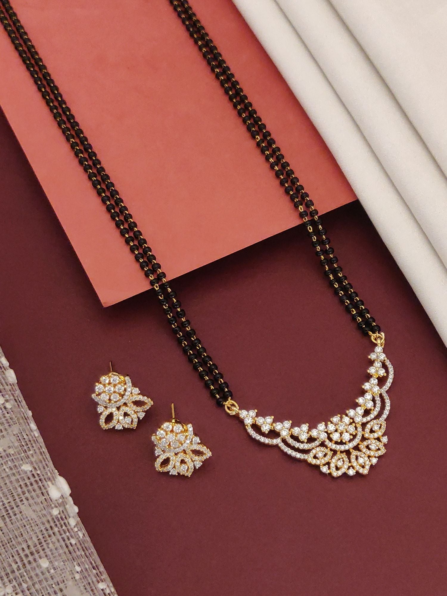 Abdesigns Opulent gold plated mangalsutra for women. Double black bead chain with floral white stone pendant plus earrings