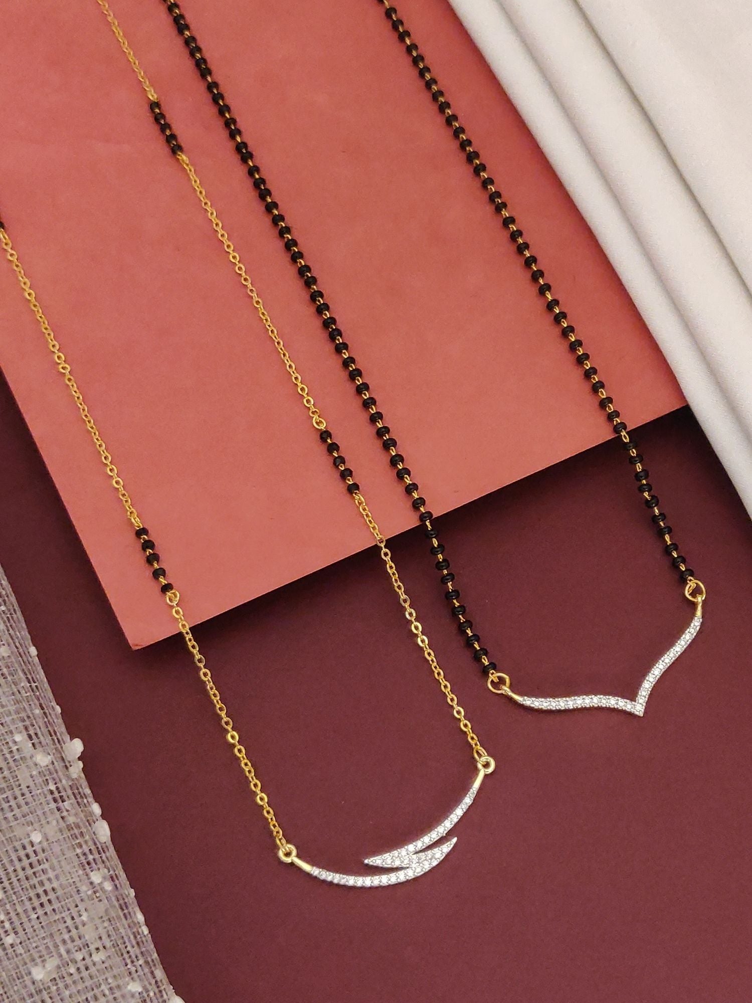 Abdesigns Set of 2 gold plated mangalsutra combo for women. Two gold chains with black beads and V shaped crystal pendants