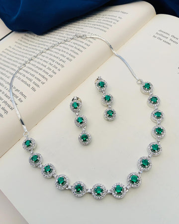 Abdesigns Silver Plated American Diamond Necklace Set with green emerald stones and matching earrings on open book