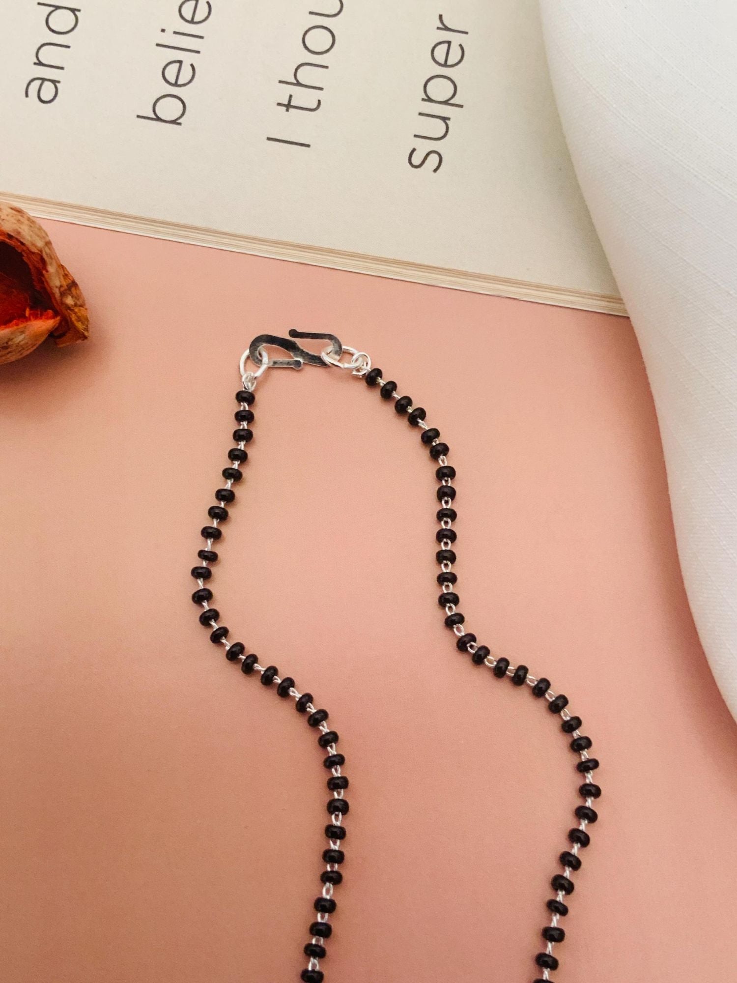 Abdesigns Sparkling CZ Mangalsutra Set black beads necklace with silver hook clasp displayed on peach background
