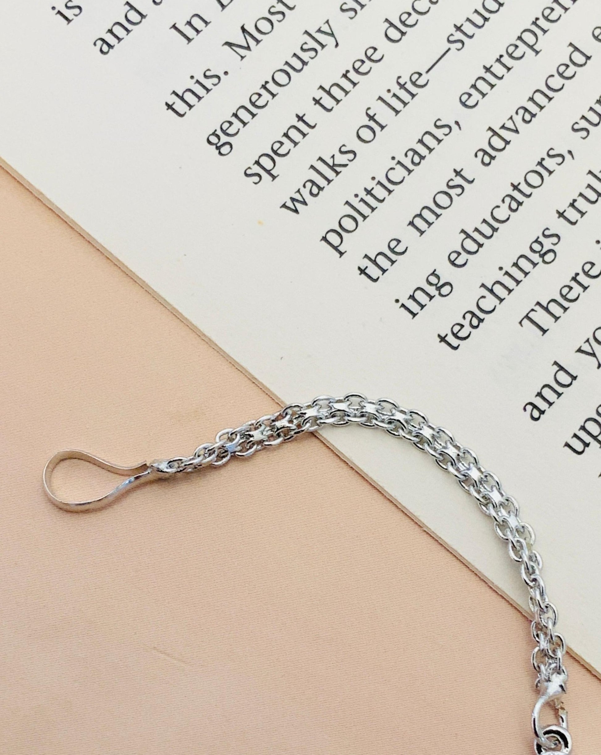 Beautiful Silver Plated American Diamond Maangtikka chain by Abdesignsjewellery lying on a beige surface near a book
