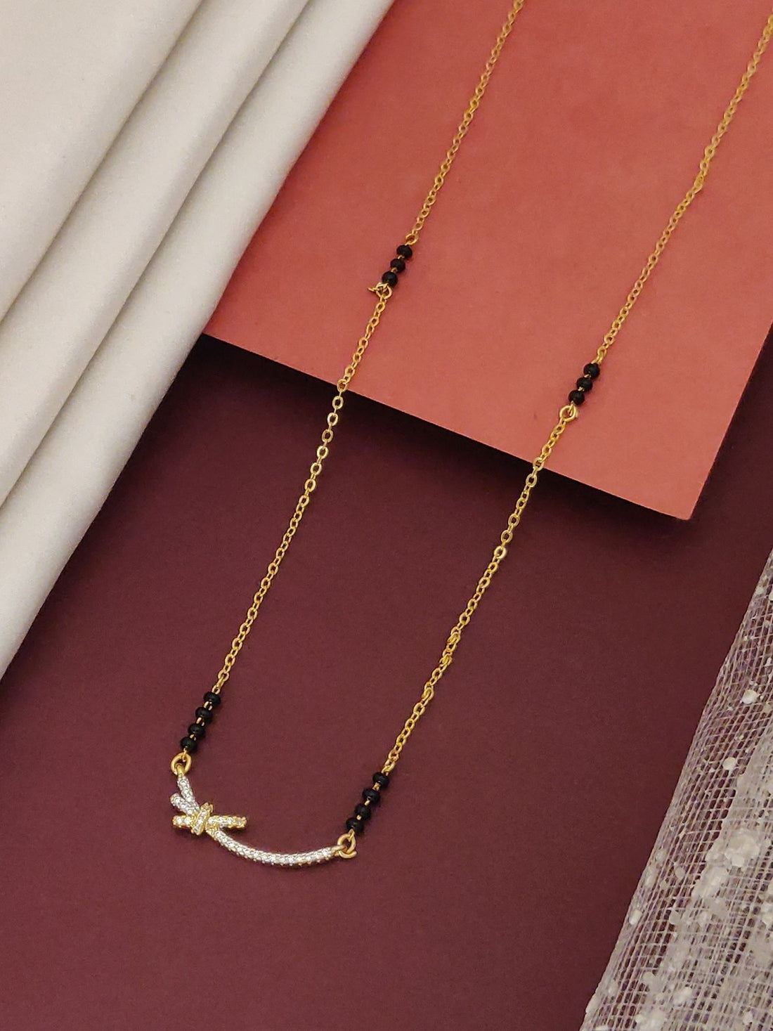 Delicate Gold Plated Mangalsutra with black beads and a small curved pendant adorned with white stones