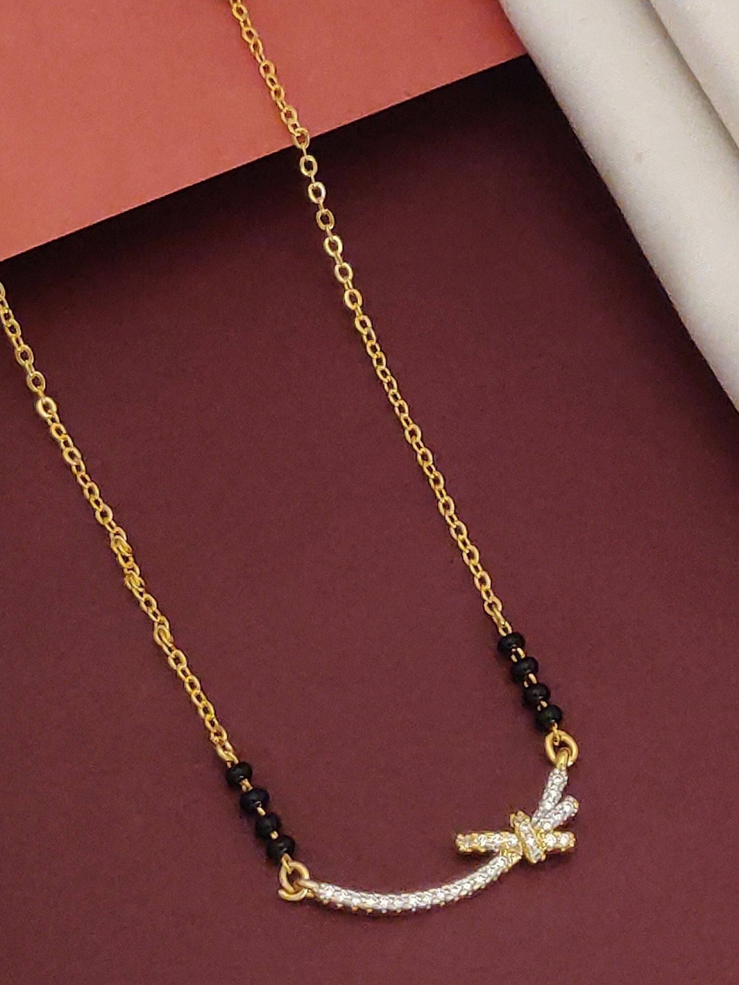 Delicate Gold Plated Mangalsutra with black beads and a sparkling curved pendant on a gold chain