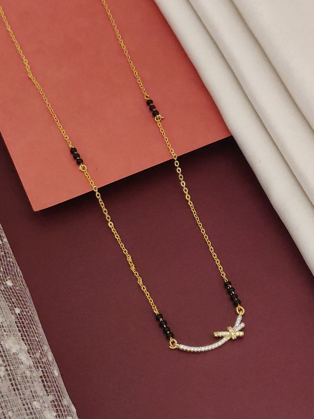 Delicate Gold Plated Mangalsutra with black beads and a small curved pendant adorned with white stones