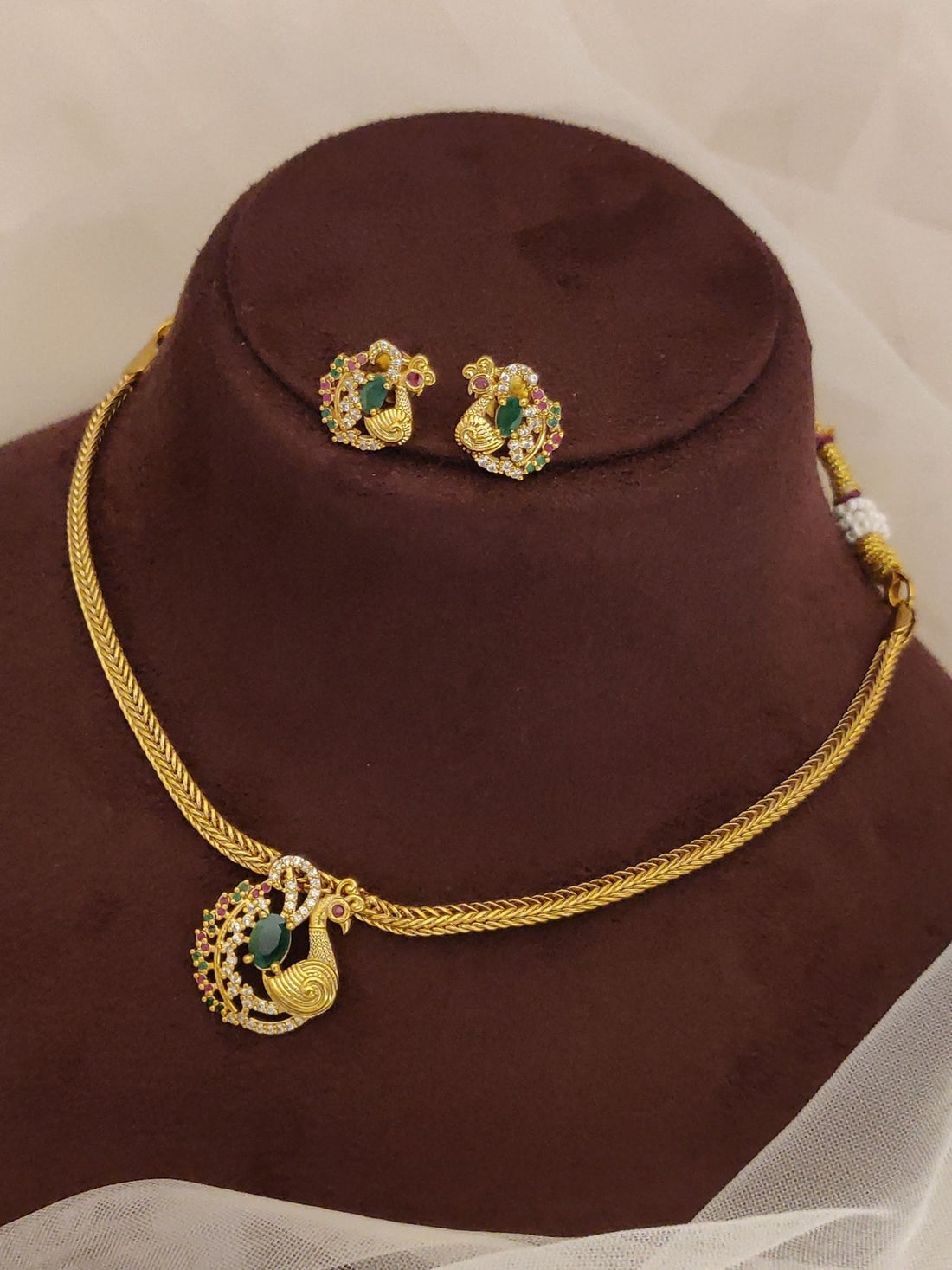 Delicated Gold Plated Peacock Style Necklace Set gold peacock pendant with green enamel and matching studs on brown display