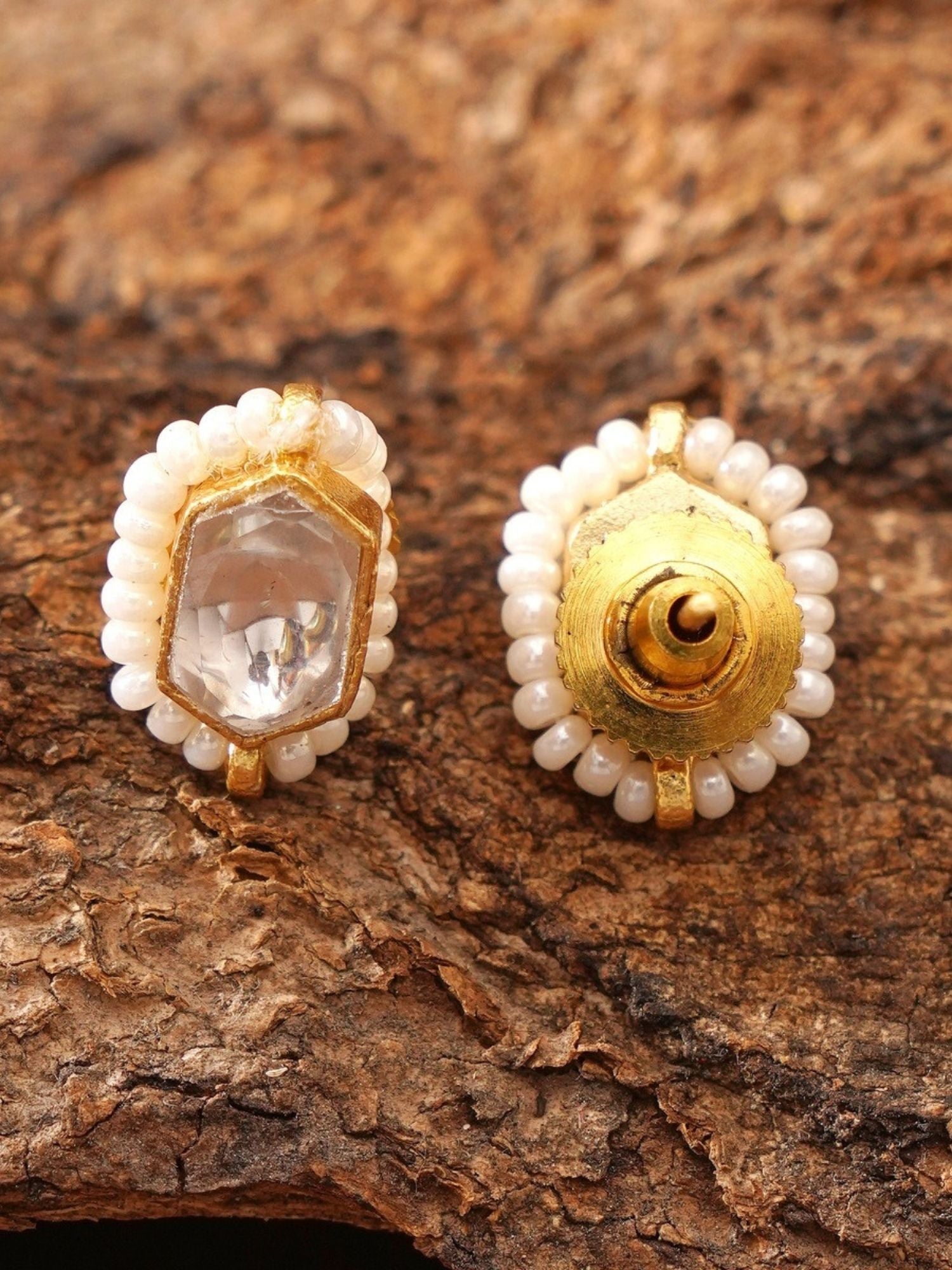 Abdesignsjewellery gold pearl halo stud earrings with clear center on wood background paired with elegant artificial ruby necklace