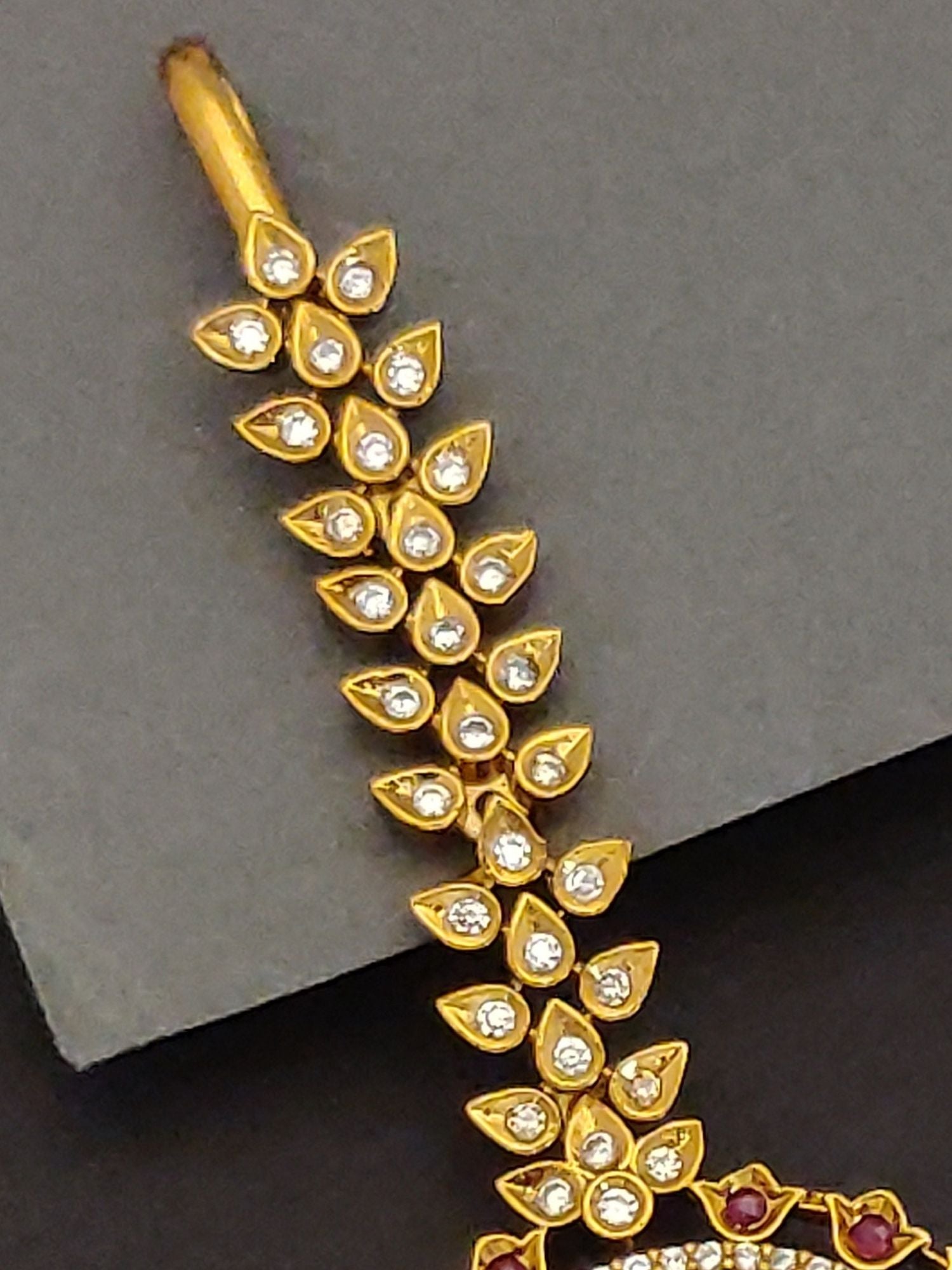 Elegant Indian bridal maangtikka gold leaf design with white stone accents and ruby red bead details