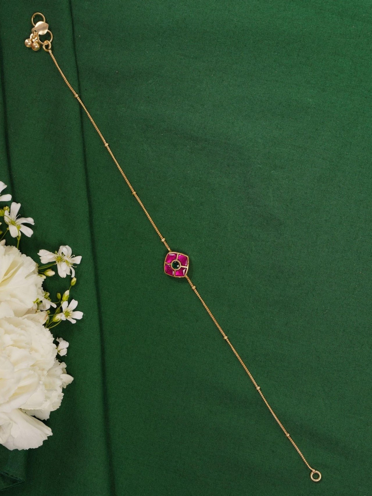 Enchanting Gold Plated Kemp Kundan Floral Anklets with delicate pink stones on green background