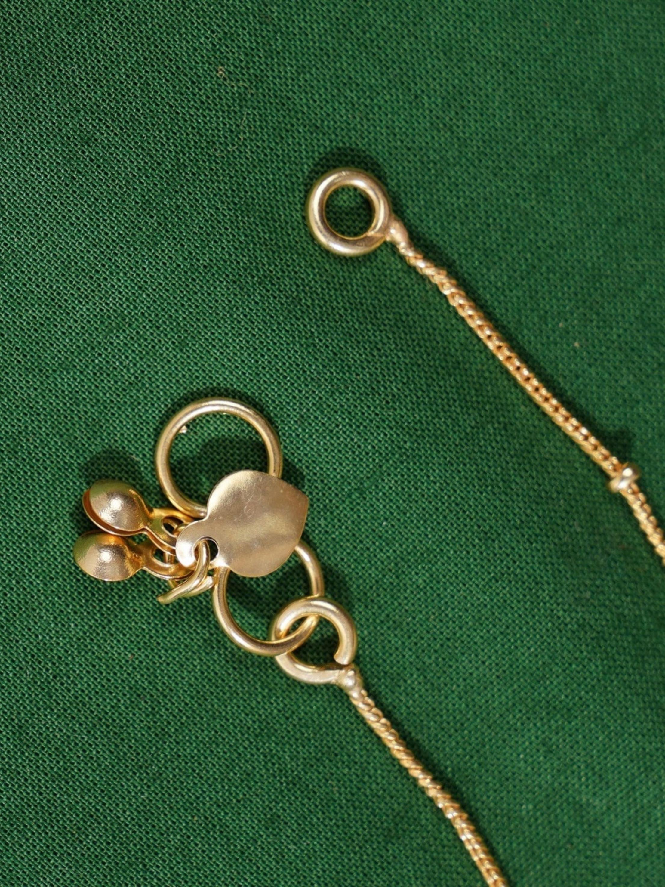 Close-up of Enchanting Gold Plated Kemp Kundan Floral Anklets chain and clasp on green fabric