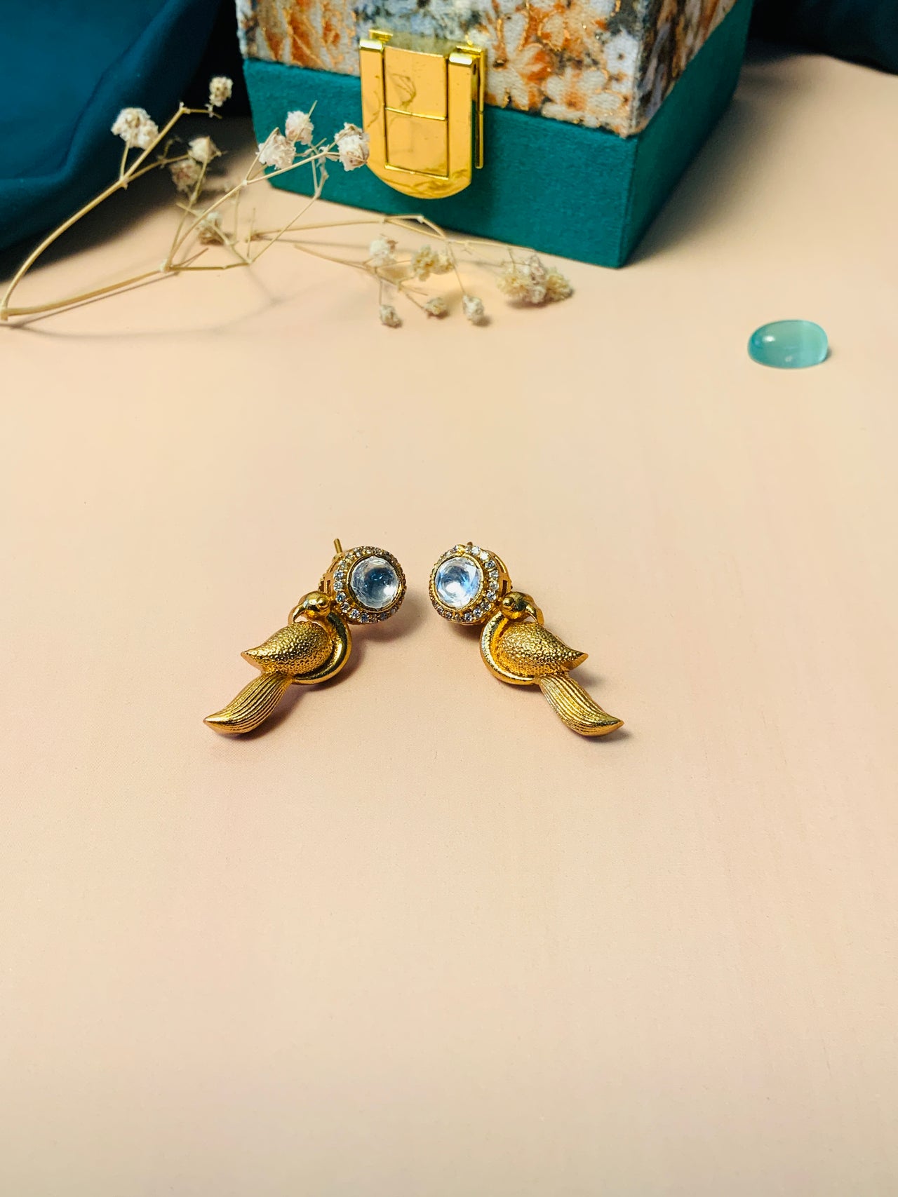 Gold Glass Kundan Polki Parrot Studs Earrings with clear stones next to decorative jewelry box