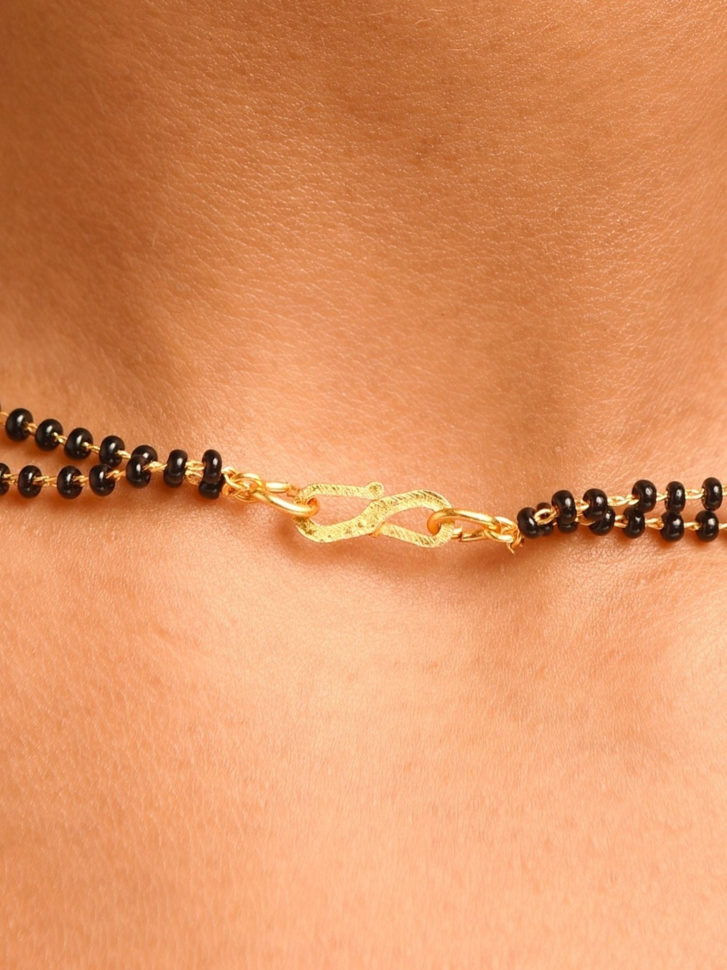 Close up of gold plated American diamond mangalsutra set with black beads and textured gold clasp on neck by Abdesignsjewellery