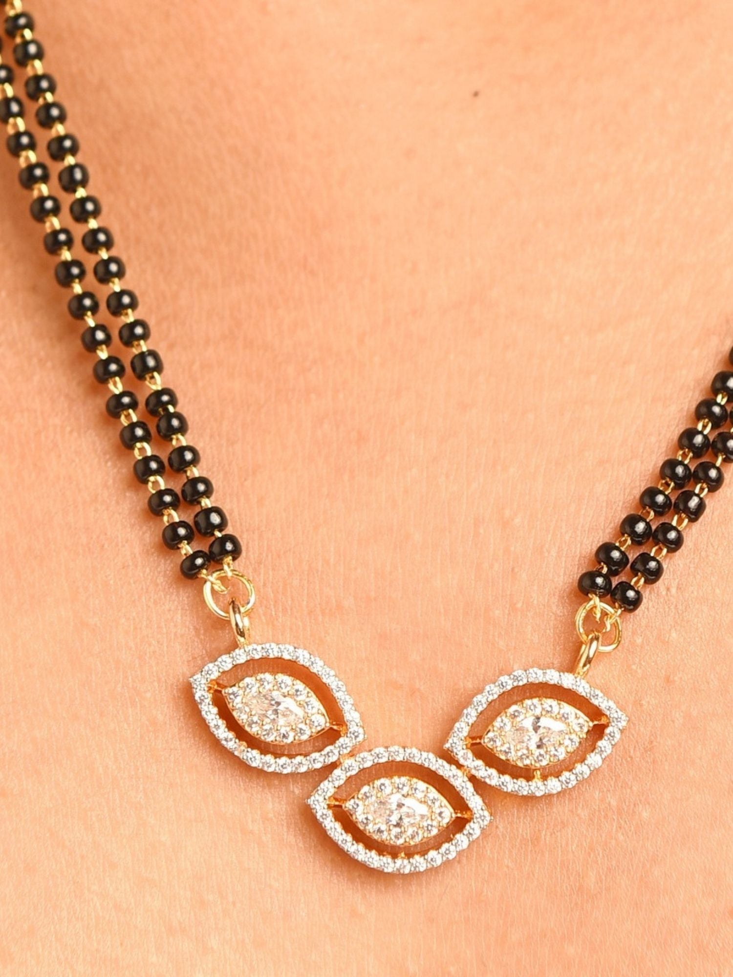 gold plated American diamond mangalsutra set with double black bead chain and three leaf shaped diamond pendants