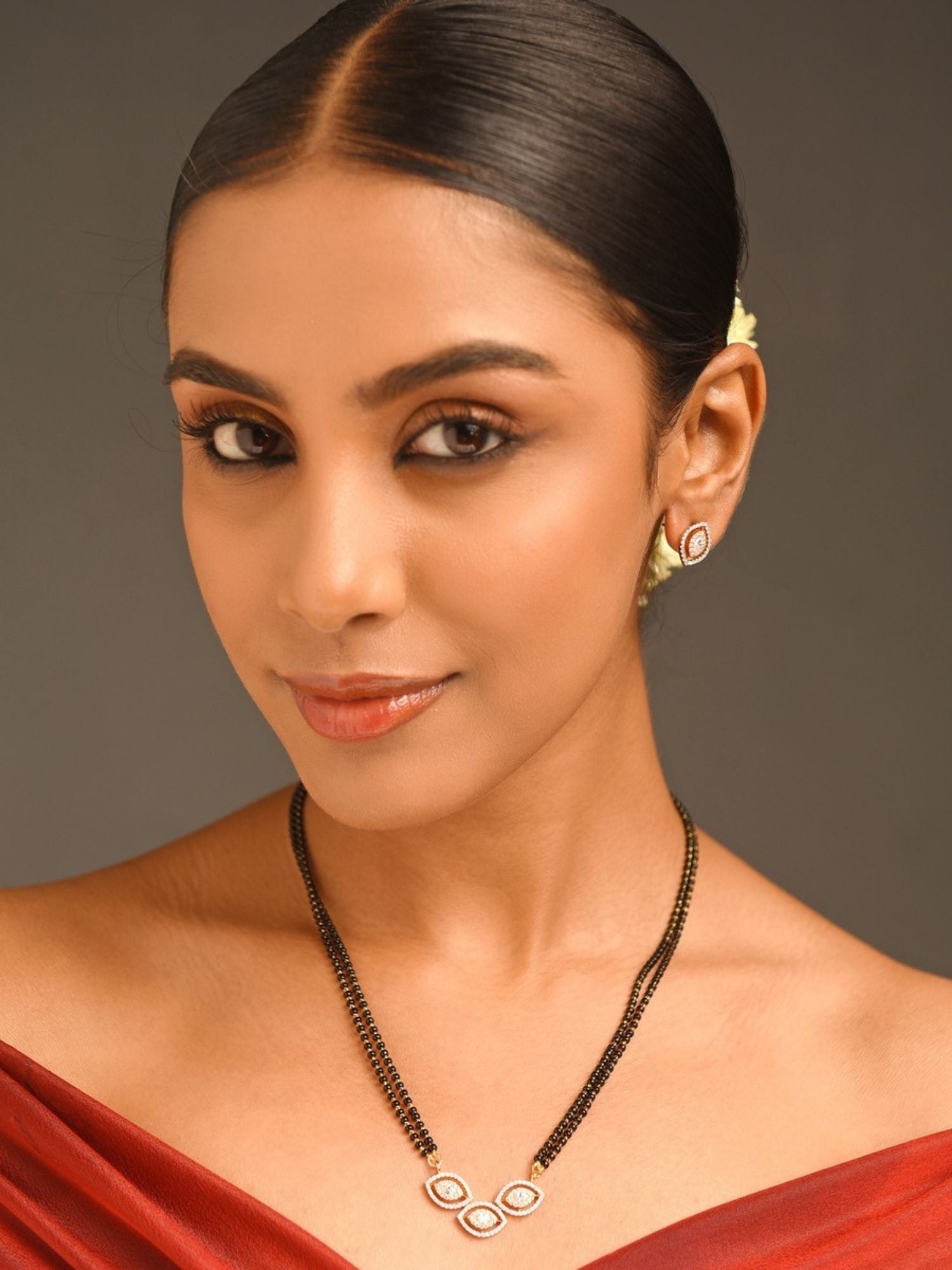 Woman model wearing gold plated American diamond mangalsutra set with double black bead chain and triple teardrop pendant