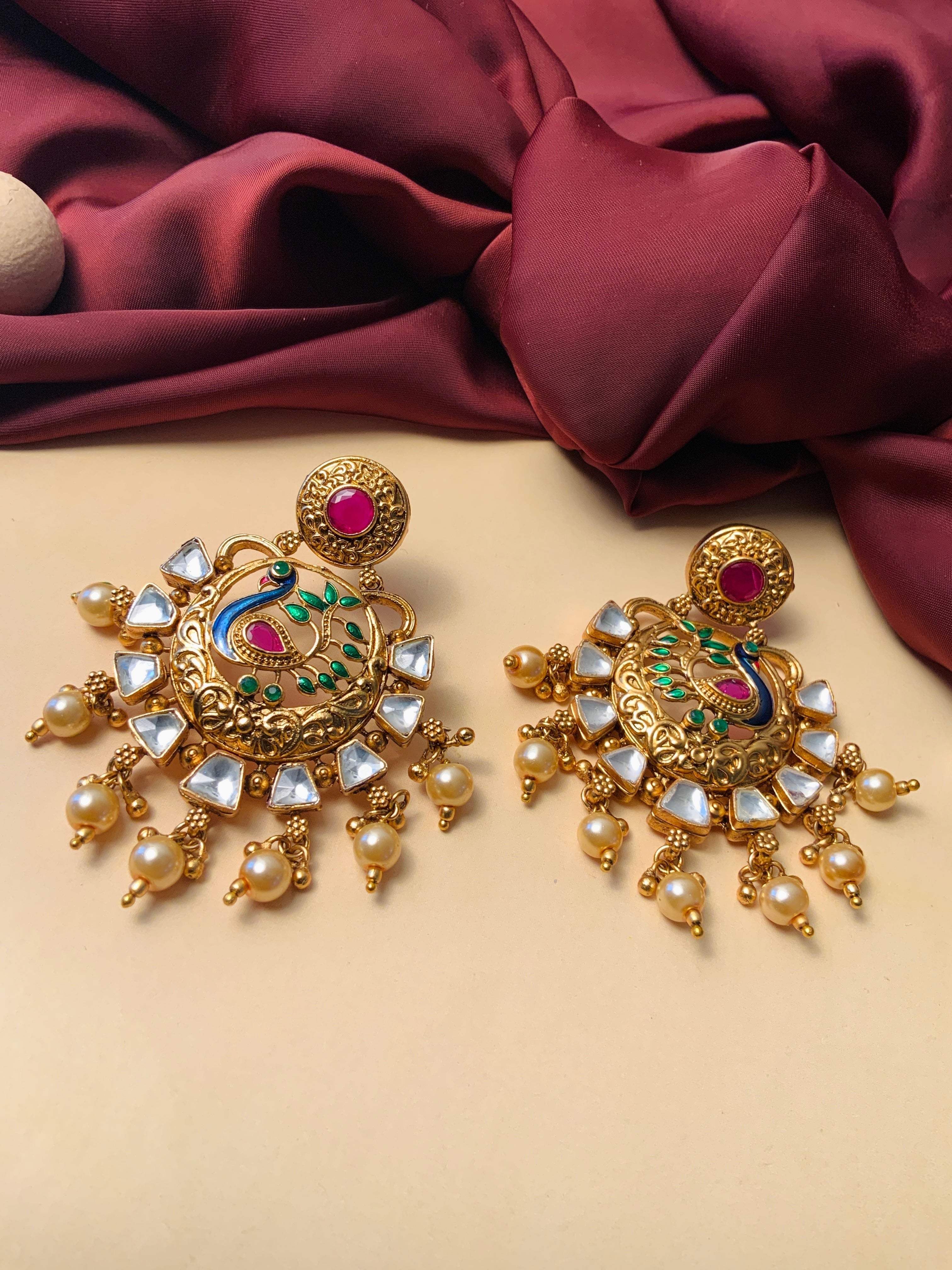 Gold Plated Antique Round Peacock Kundan Earrings with pearl drops green enamel and kundan stones on beige backdrop